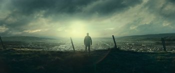 A man standing on top of a hill near the ocean