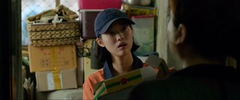 Movie still from “Parasite” (2019), directed by Bong Joon Ho – A woman in an orange shirt holding a box in her hands; Close Up shot, Over the shoulder angle