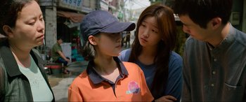 Movie still from “Parasite” (2019), directed by Bong Joon Ho – Two young women standing next to each other on the street; Medium shot, Over the shoulder angle