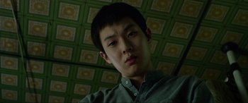 Movie still from “Parasite” (2019), directed by Bong Joon Ho – A young man is looking at the camera; Close Up shot, Low angle