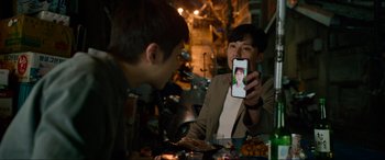 Movie still from “Parasite” (2019), directed by Bong Joon Ho – A man taking a picture of another man with a cell phone; Extreme Close Up shot, Over the shoulder angle