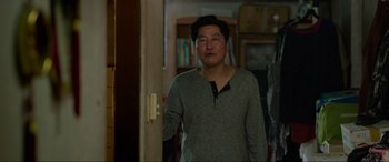 Movie still from “Parasite” (2019), directed by Bong Joon Ho – A man standing in front of a door in a room; Medium shot, Over the shoulder angle