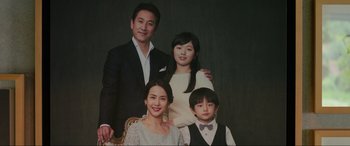 Movie still from “Parasite” (2019), directed by Bong Joon Ho – A group of people posing for a picture in front of a black background; Medium shot, Low angle