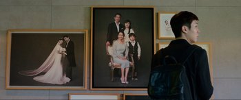 Movie still from “Parasite” (2019), directed by Bong Joon Ho – A picture of a family sitting on a chair; Medium shot, Over the shoulder angle