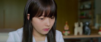 Movie still from “Parasite” (2019), directed by Bong Joon Ho – A young woman with long black hair looking down at her face; Close Up shot, Low angle