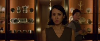 Movie still from “Parasite” (2019), directed by Bong Joon Ho – A woman in a brown dress standing in front of a mirror; Close Up shot, Over the shoulder angle