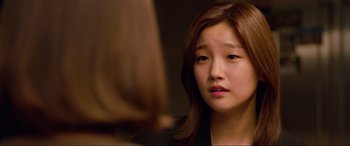 Movie still from “Parasite” (2019), directed by Bong Joon Ho – A young woman looking at the camera in front of a mirror; Close Up shot, Over the shoulder angle