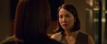 Movie still from “Parasite” (2019), directed by Bong Joon Ho – A woman looking at the camera while sitting in front of a mirror; Close Up shot, Over the shoulder angle