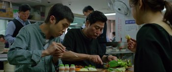 Movie still from “Parasite” (2019), directed by Bong Joon Ho – A man and a boy cutting vegetables on a cutting board; Medium shot, Over the shoulder angle