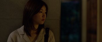 Movie still from “Parasite” (2019), directed by Bong Joon Ho – A young woman is sitting against a wall; Close Up shot, Over the shoulder angle