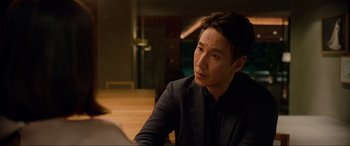 Movie still from “Parasite” (2019), directed by Bong Joon Ho – A man sitting at a table looking at something; Close Up shot, Over the shoulder angle