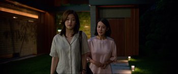 Movie still from “Parasite” (2019), directed by Bong Joon Ho – Two young asian women standing next to each other on the street; Medium shot, Over the shoulder angle
