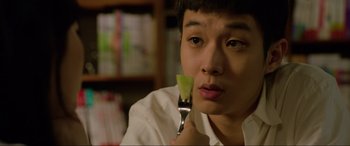 Movie still from “Parasite” (2019), directed by Bong Joon Ho – A man holding a fork with a piece of fruit in front of his face; Close Up shot, Over the shoulder angle