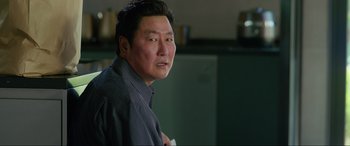 Movie still from “Parasite” (2019), directed by Bong Joon Ho – An asian man in a blue shirt is looking at the camera; Close Up shot, Over the shoulder angle