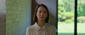 Movie still from “Parasite” (2019), directed by Bong Joon Ho – A woman in a checkered jacket looking at the camera; Close Up shot, Low angle
