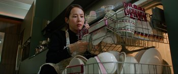 Movie still from “Parasite” (2019), directed by Bong Joon Ho – A woman in an apron is holding a phone; Medium shot, Low angle