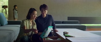 Movie still from “Parasite” (2019), directed by Bong Joon Ho – Two women are looking at an open box; Medium shot, Over the shoulder angle
