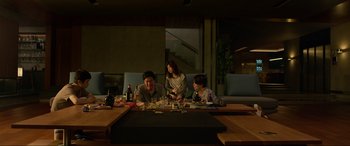 Movie still from “Parasite” (2019), directed by Bong Joon Ho – A group of people sitting at a table with wine glasses; Wide shot, Low angle
