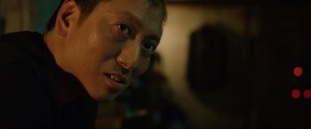 Movie still from “Parasite” (2019), directed by Bong Joon Ho – A young man's face in a dark room; Close Up shot, Low angle