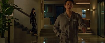 Movie still from “Parasite” (2019), directed by Bong Joon Ho – A man and a woman standing in front of each other in pajamas; Medium shot, Low angle