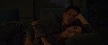 Movie still from “Parasite” (2019), directed by Bong Joon Ho – A man and a woman laying on a couch; Medium shot, Overhead angle