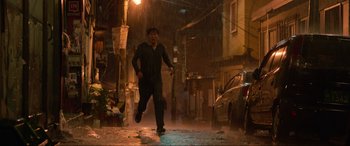 Movie still from “Parasite” (2019), directed by Bong Joon Ho – A man is running in the rain on the street; Wide shot, Low angle