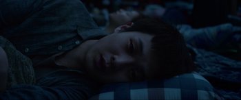 Movie still from “Parasite” (2019), directed by Bong Joon Ho – A young man laying on top of a bed; Close Up shot, Overhead angle