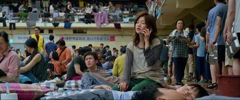 Movie still from “Parasite” (2019), directed by Bong Joon Ho – A woman sitting next to a man on the ground; Medium shot, High angle