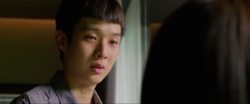 Movie still from “Parasite” (2019), directed by Bong Joon Ho – A young asian man looking into a mirror; Close Up shot, Over the shoulder angle