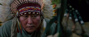 Movie still from “Parasite” (2019), directed by Bong Joon Ho – An older man wearing a native american headdress; Close Up shot, Over the shoulder angle