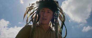 Movie still from “Parasite” (2019), directed by Bong Joon Ho – A man wearing a native american headdress; Close Up shot, Low angle
