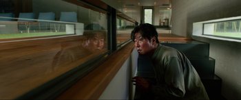 Movie still from “Parasite” (2019), directed by Bong Joon Ho – A man looking out of a window at another man; Medium shot, High angle