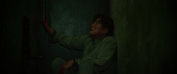Movie still from “Parasite” (2019), directed by Bong Joon Ho – A man sitting on the ground in a dark room; Medium shot, Overhead angle