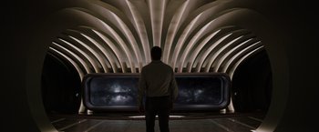 Movie still from “Passengers” (2016), directed by Morten Tyldum – A man standing in front of a wall with lights on it; Wide shot, Low angle