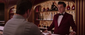 Movie still from “Passengers” (2016), directed by Morten Tyldum – A man in a red jacket standing at a bar; Medium shot, Over the shoulder angle