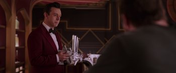 Movie still from “Passengers” (2016), directed by Morten Tyldum – A man in a red tuxedo holding a glass of wine; Medium shot, Over the shoulder angle