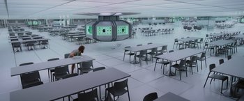 Movie still from “Passengers” (2016), directed by Morten Tyldum – A woman is standing at a table in a room; Extreme Wide shot, High angle