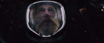 Movie still from “Passengers” (2016), directed by Morten Tyldum – A man with a long beard wearing a space helmet; Close Up shot, Overhead angle