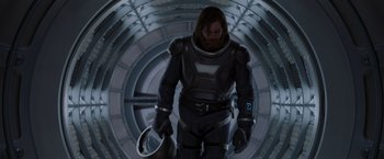 Movie still from “Passengers” (2016), directed by Morten Tyldum – A man in a spacesuit is holding something in his hand; Medium shot, Low angle