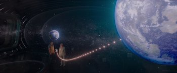 Movie still from “Passengers” (2016), directed by Morten Tyldum – Two people standing in front of the earth in a room; Extreme Wide shot, High angle