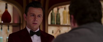 Movie still from “Passengers” (2016), directed by Morten Tyldum – A man in a red jacket and a black bow tie; Close Up shot, Over the shoulder angle