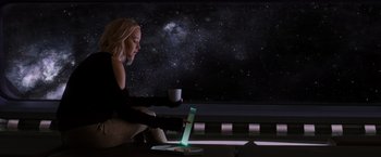 Movie still from “Passengers” (2016), directed by Morten Tyldum – A woman sitting in front of a laptop computer; Medium shot, Over the shoulder angle