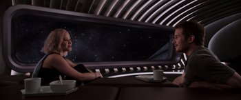 Movie still from “Passengers” (2016), directed by Morten Tyldum – A woman sitting at a table in front of a window; Medium shot, Low angle