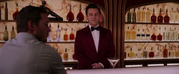 Movie still from “Passengers” (2016), directed by Morten Tyldum – A man standing at a bar wearing a suit and bow tie; Medium shot, Over the shoulder angle