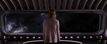 Movie still from “Passengers” (2016), directed by Morten Tyldum – A woman standing in front of a window looking out at the stars; Medium shot, Low angle