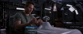 Movie still from “Passengers” (2016), directed by Morten Tyldum – A man working on an object in a room; Medium shot, High angle