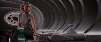 Movie still from “Passengers” (2016), directed by Morten Tyldum – A woman sitting on the ground holding a coffee cup; Medium shot, Over the shoulder angle