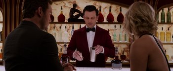 Movie still from “Passengers” (2016), directed by Morten Tyldum – A man in a red jacket and a black bow tie; Medium shot, Over the shoulder angle