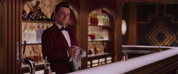 Movie still from “Passengers” (2016), directed by Morten Tyldum – A man in a red jacket is holding a napkin; Medium shot, Over the shoulder angle