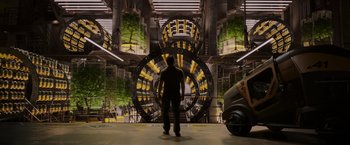 Movie still from “Passengers” (2016), directed by Morten Tyldum – A man standing in front of a large machine; Wide shot, Low angle